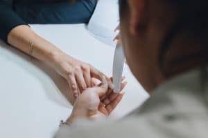 Manicurist buffing and filing a client's nail during a manicure