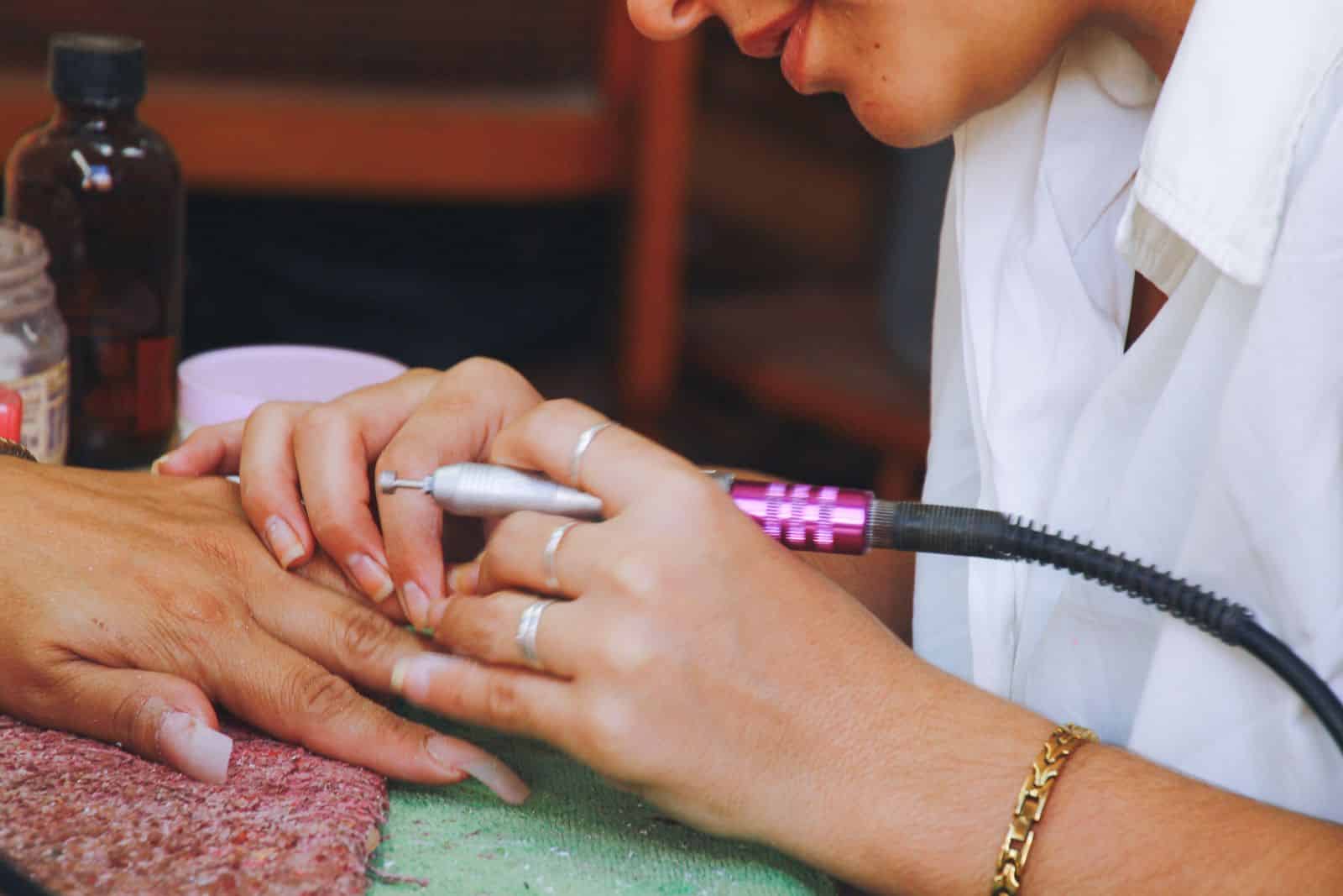 Nail technician holding an electric nail sander used to shape extensions