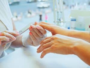 Nail technician filing a client's hand during a manicure appointment