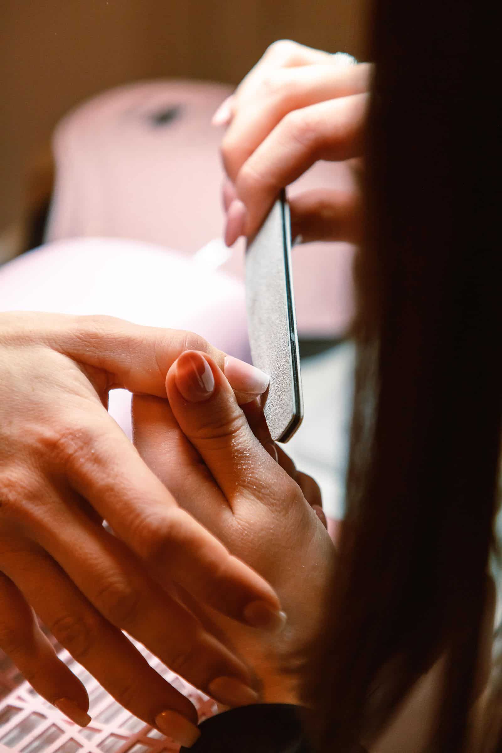 Nail technician filing a nail during prep, buffing off the natural shine
