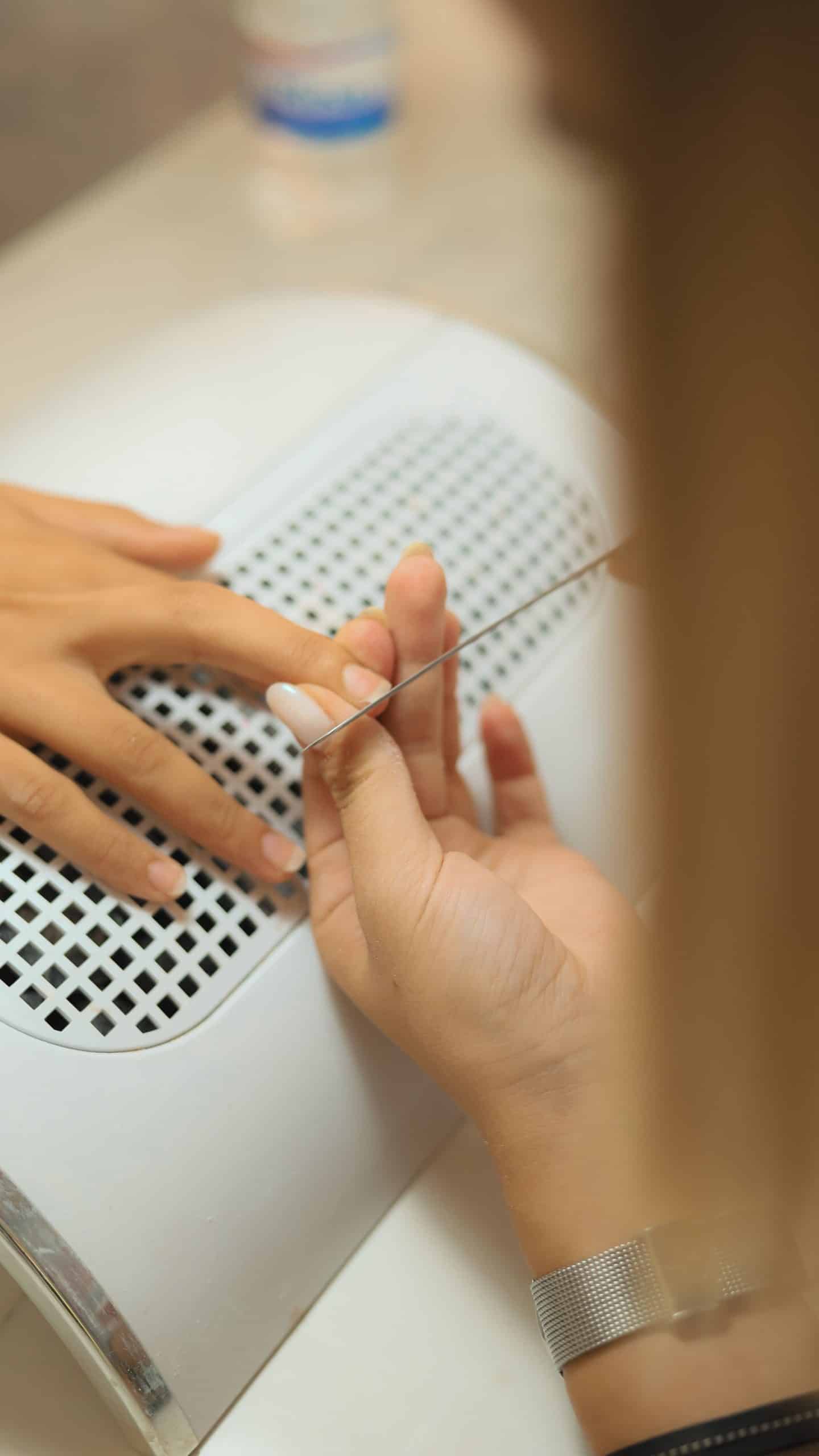 Close-up of a manicurist filing the regrowth area before a gel nail fill