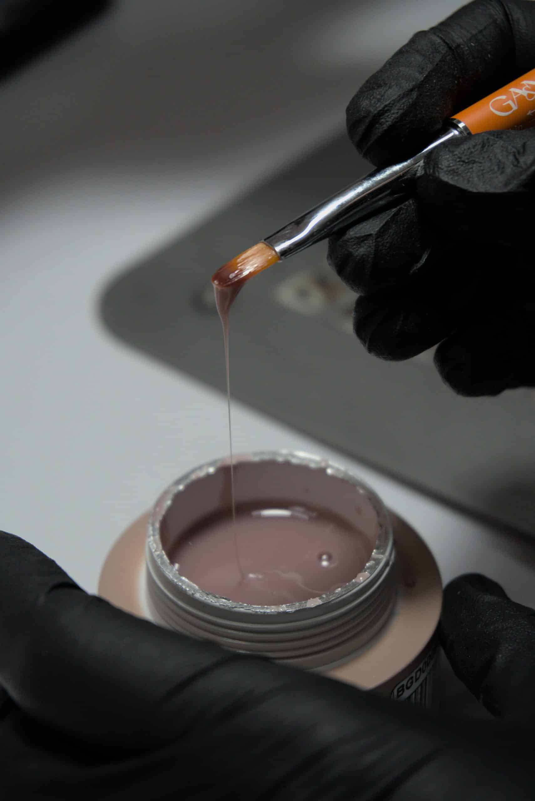 Applying builder gel with a brush to build the nail's arch