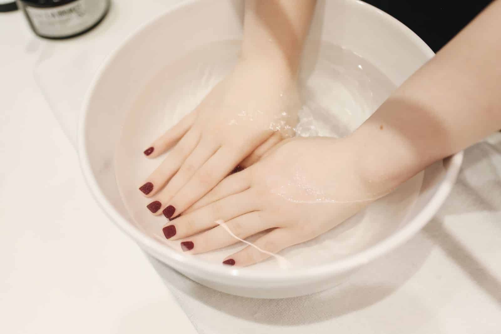 Hand soaking in a bowl of water, similar to an acetone soak used to remove nails