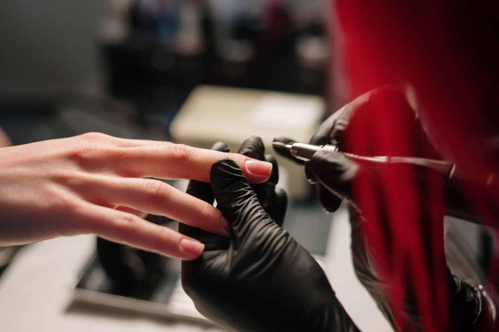 Close-up of an e-file smoothing the surface of a manicured nail