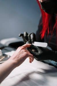 Manicurist in gloves working on a client's nails