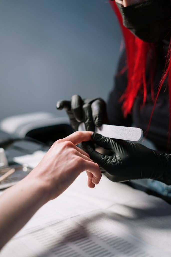 Manicurist in gloves working on a client's nails