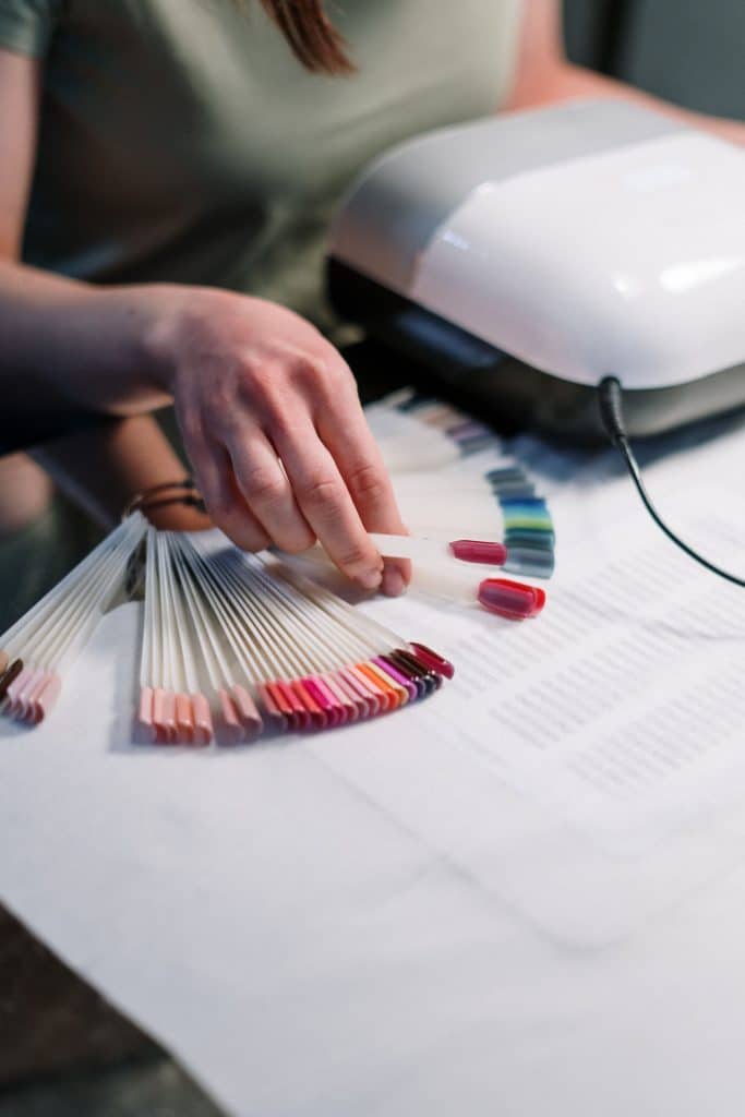 Person holding artificial nail tip samples used for polygel extensions