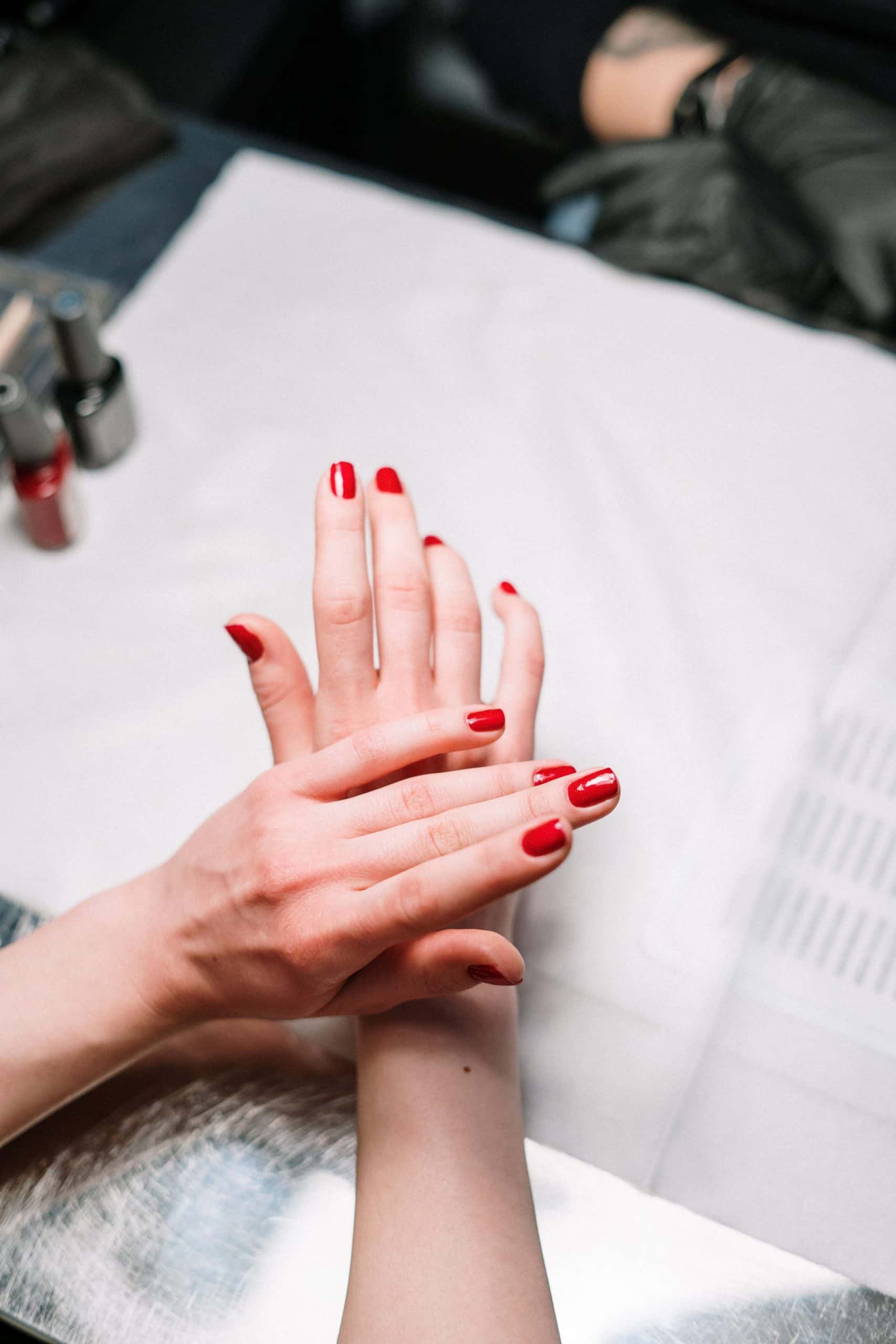Finished glossy red gel manicure at a nail salon