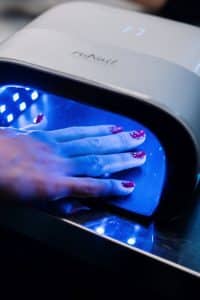 Hand placed inside a UV LED nail lamp curing gel polish