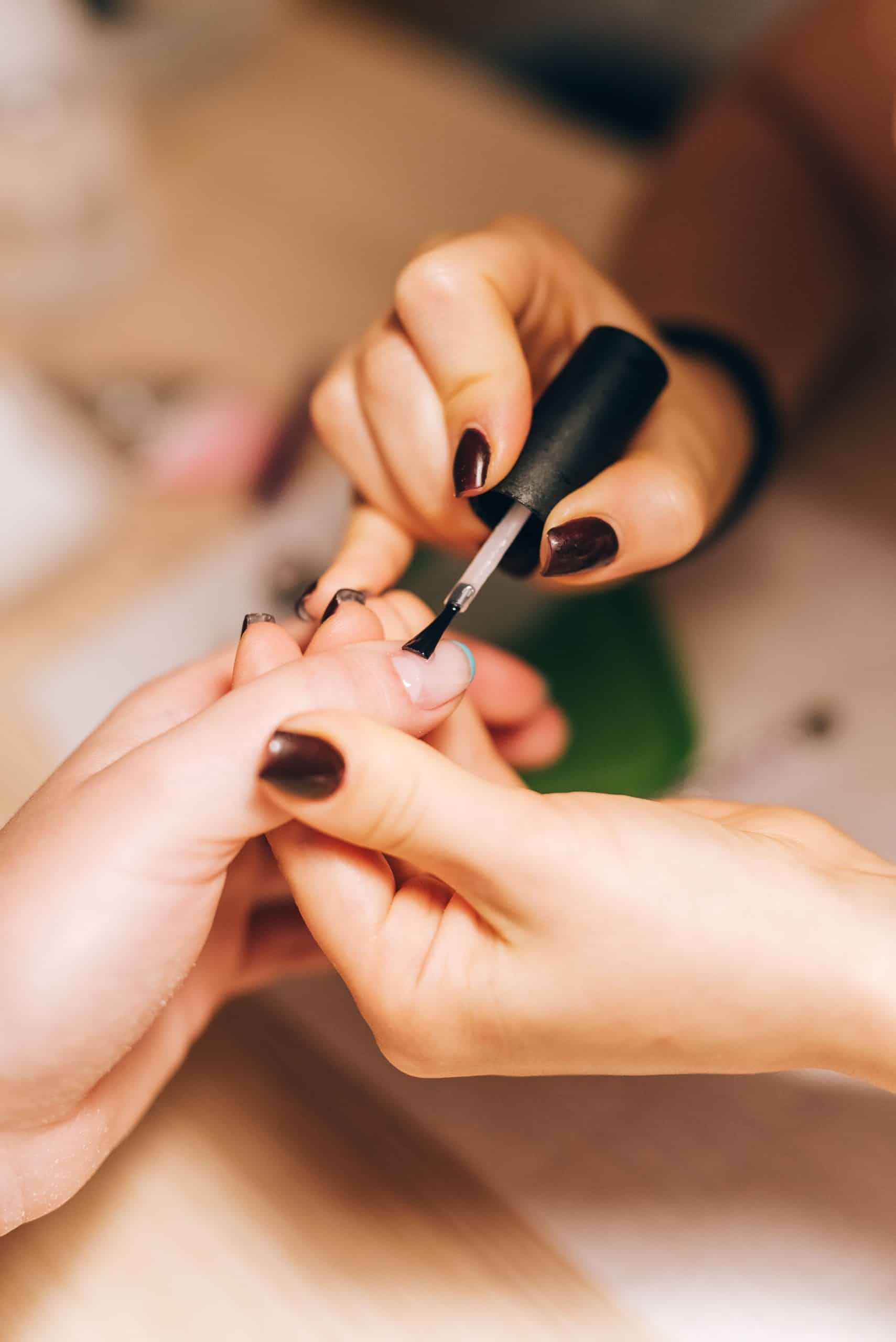 Nail technician applying gel polish to a client's nails during a manicure appointment
