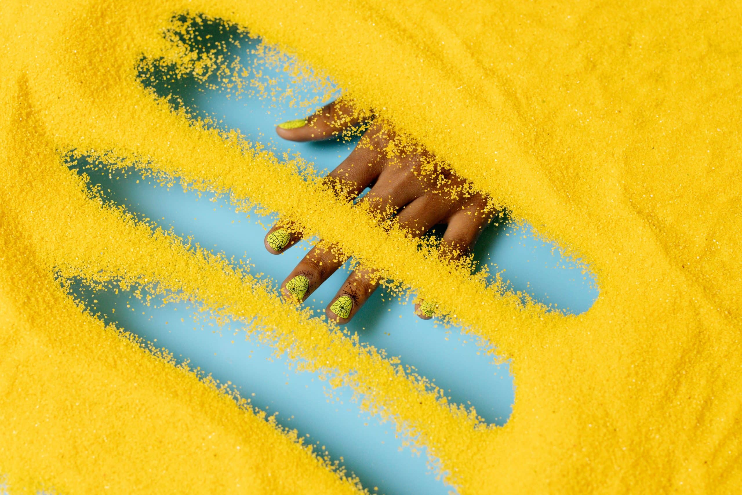 Hand with manicured nails dipped into colored dip powder