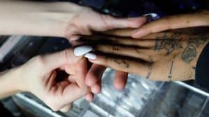 Nail technician pressing a false nail onto a client's finger