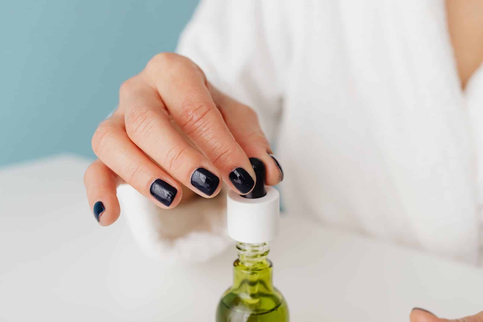 Dropper applying cuticle oil to a manicured nail