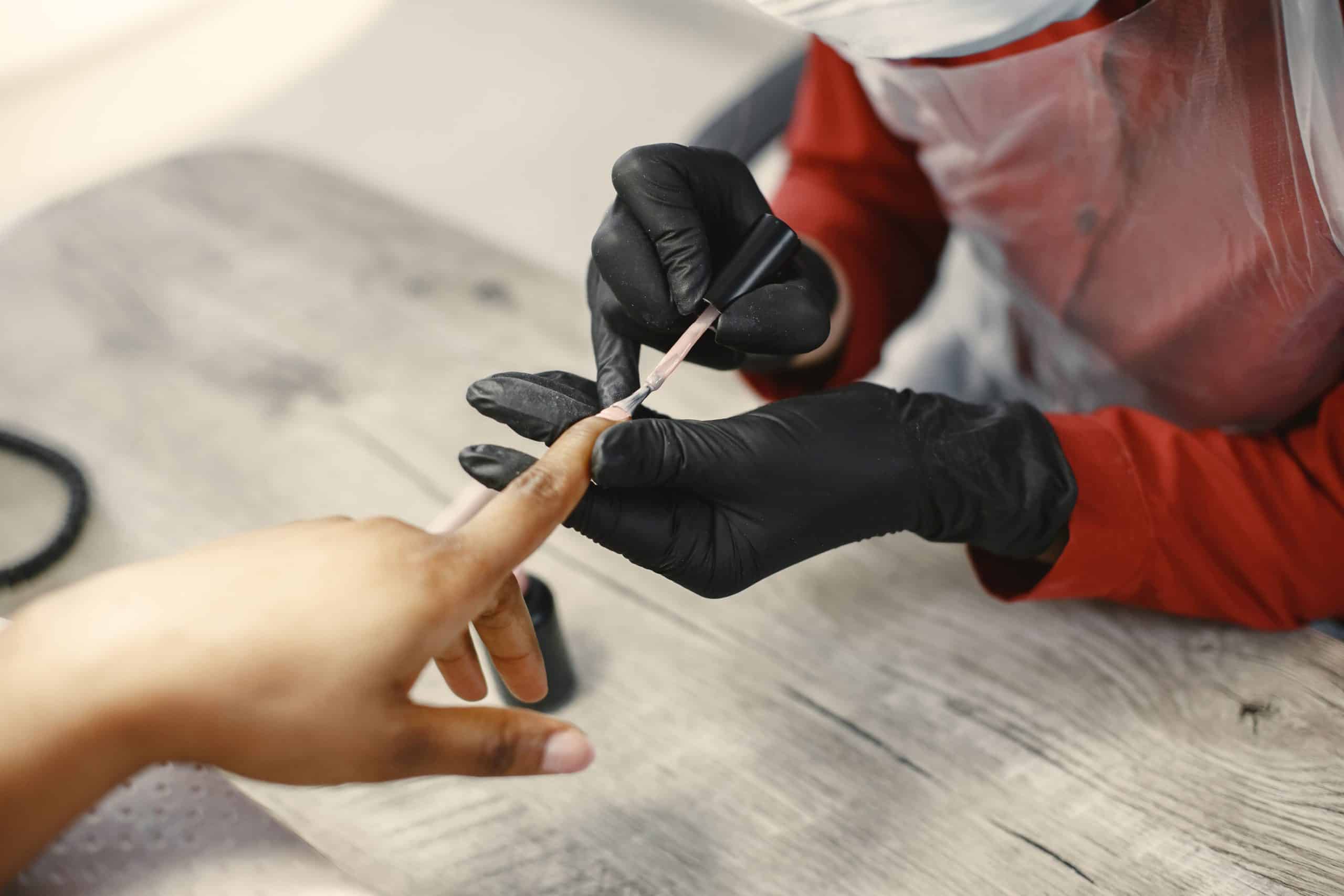 Nail technician applying gel polish to a client's nail