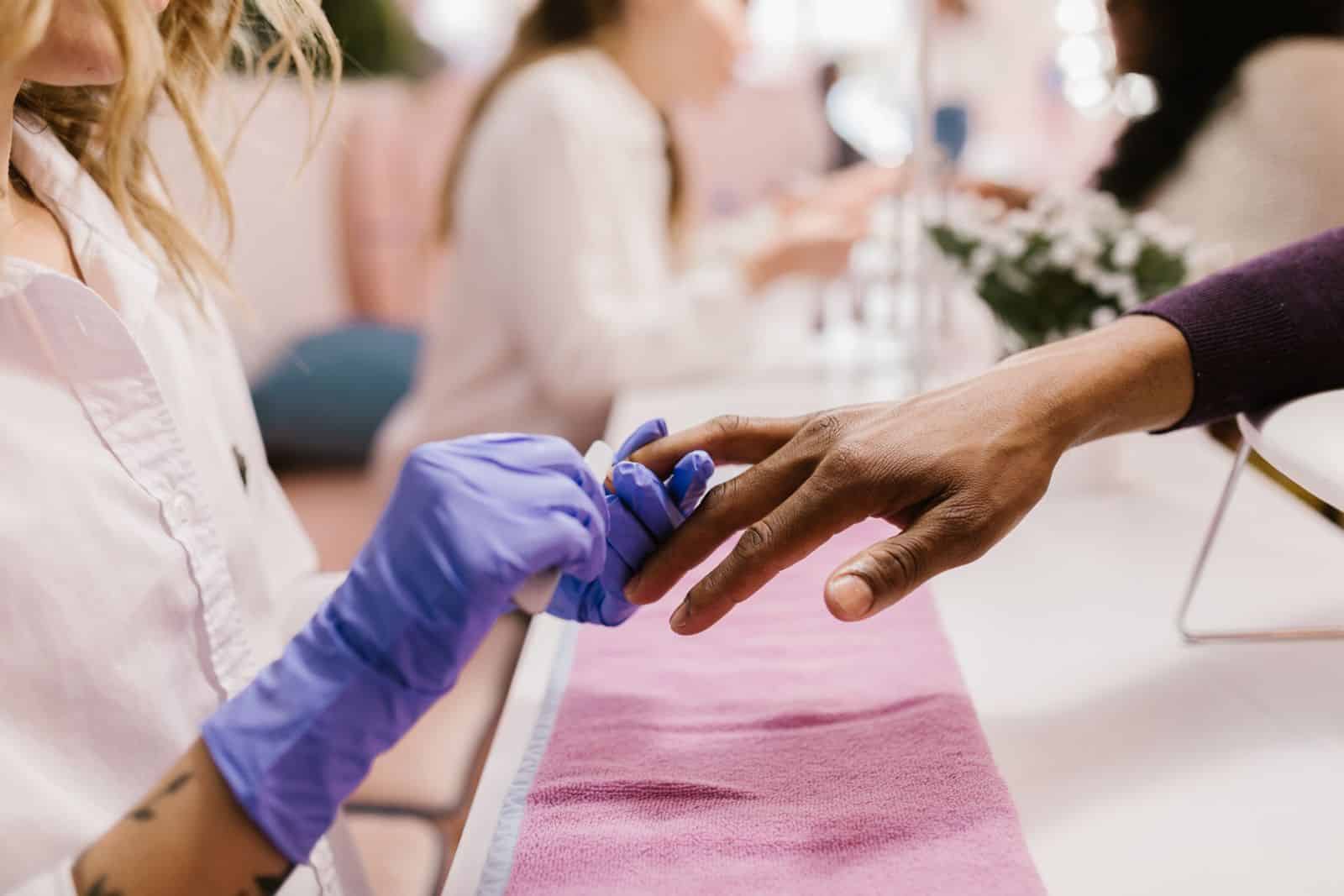 Manicurist filing and shaping a builder gel nail with focused attention