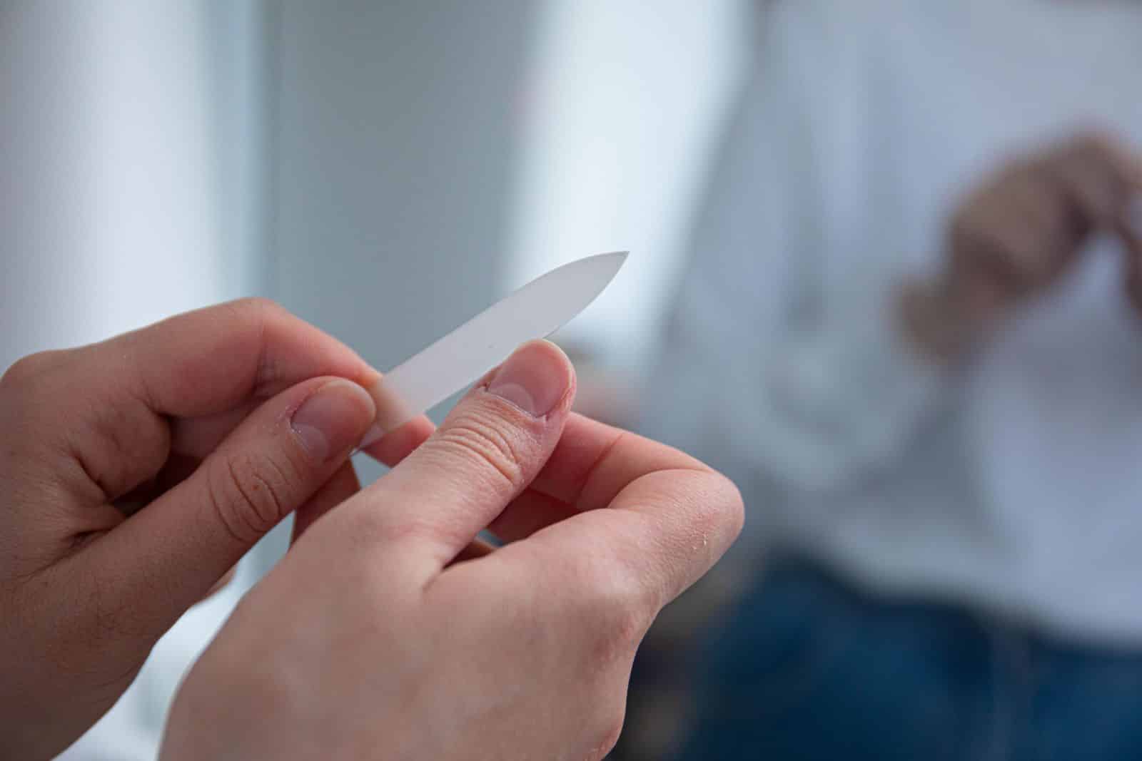 Person shaping a nail extension with a glass nail file