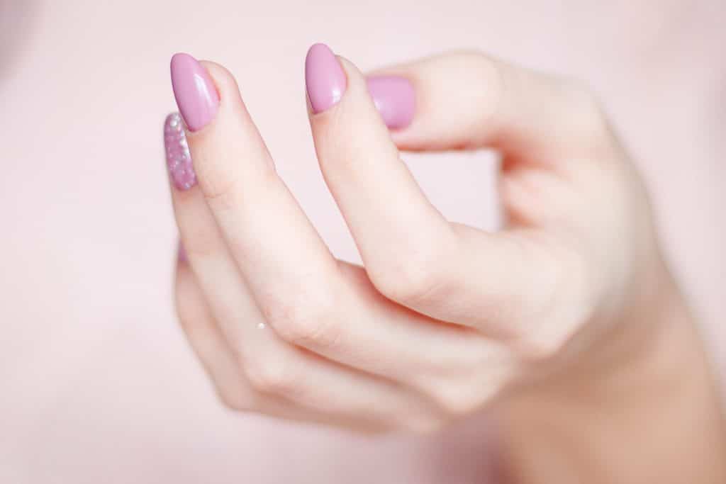 Close-up of a person's hand with a glossy pink manicure