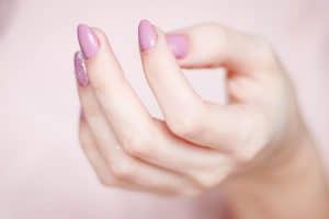 Close-up of a person's hand with a glossy pink manicure