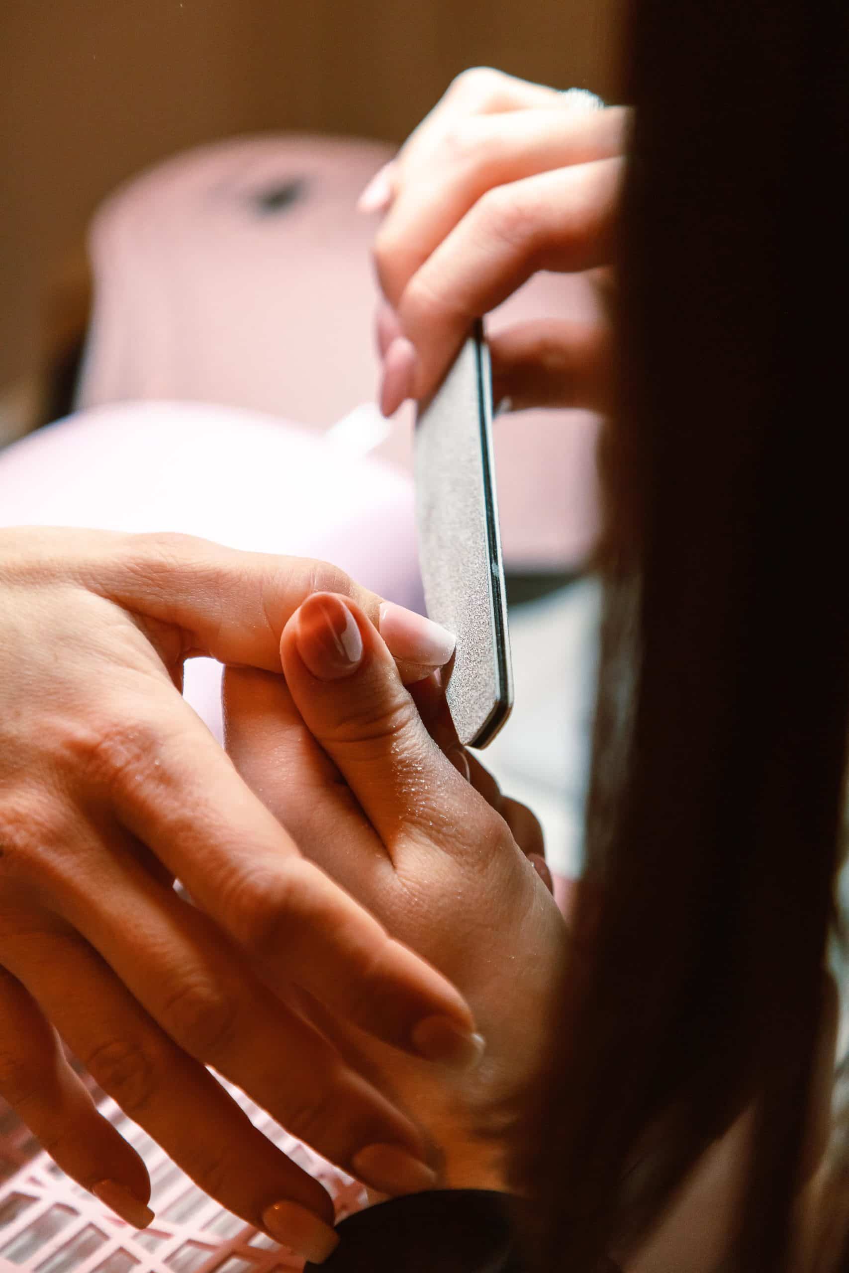 Nail file being used to buff the top layer of acrylic before soaking in acetone